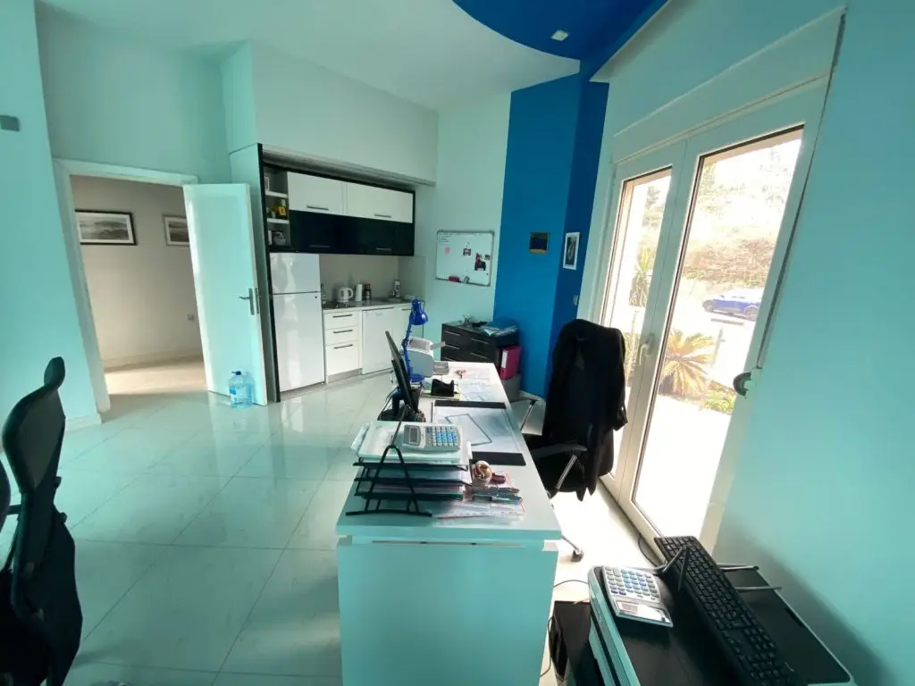 Office area with desks, chairs, kitchenette, and glass doors
