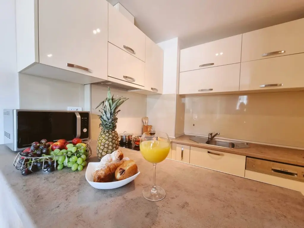 Kitchen counter with fruit basket, pineapple, pastries, and orange juice