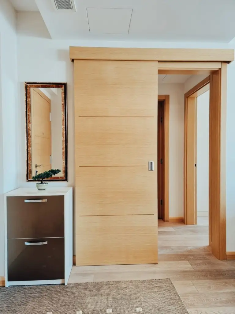 Hallway with wooden sliding door, mirror, and shoe cabinet