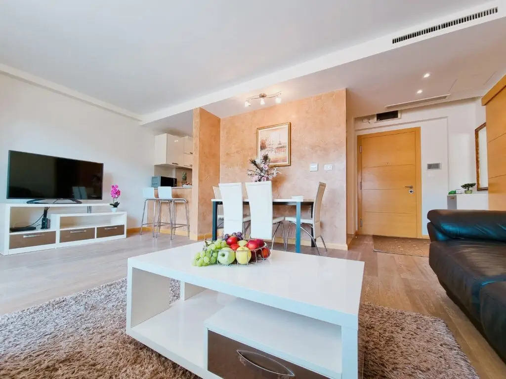 Open-plan living room with TV, dining table, and coffee table fruit basket