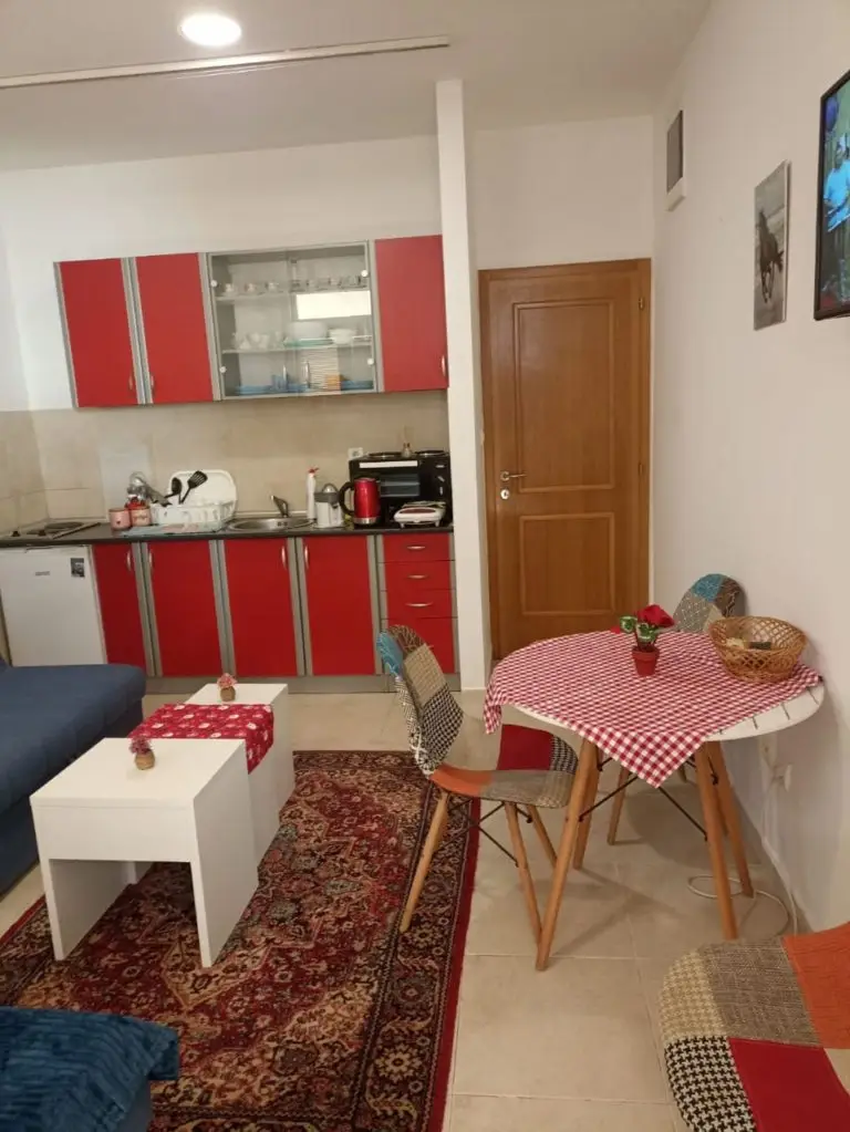 Compact studio apartment with red kitchen cabinets and dining table