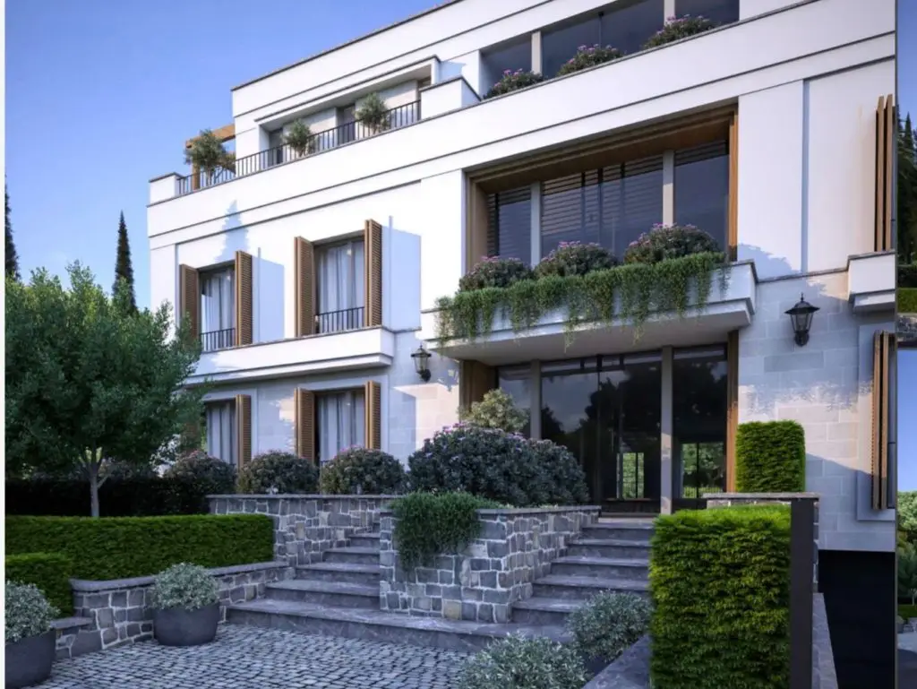 Modern white apartment building with balconies and landscaped entrance