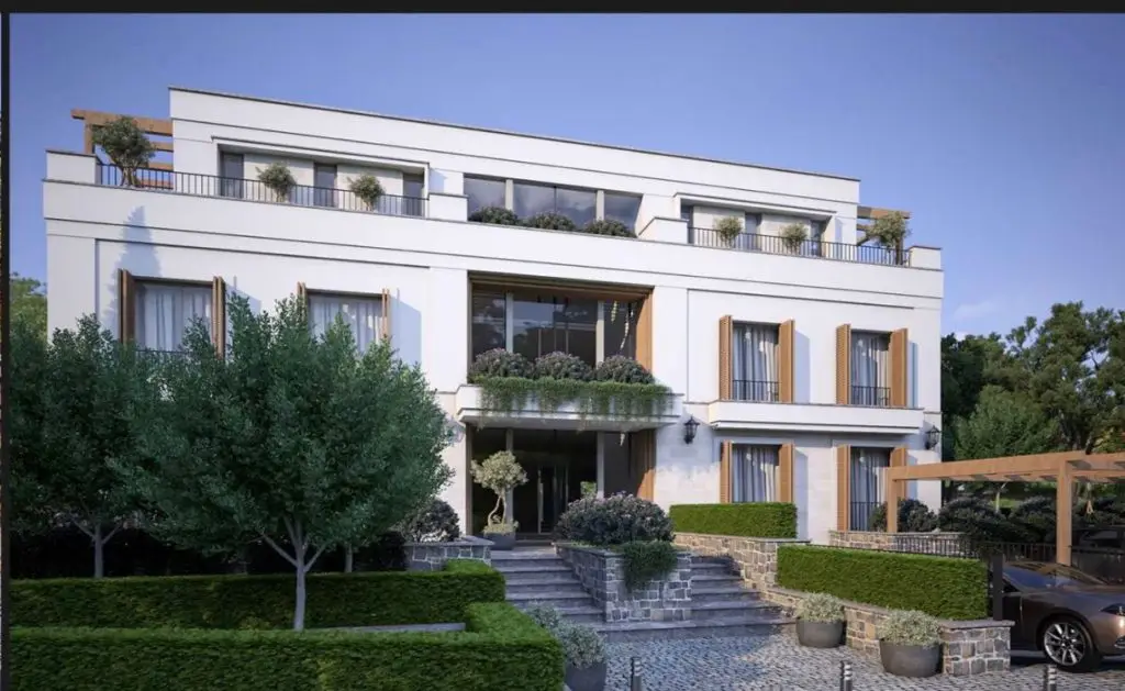 Modern white apartment building with balconies and landscaped garden