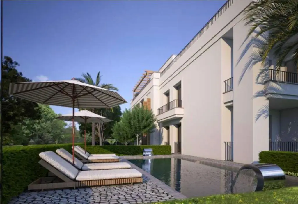 Apartment building with pool, sun loungers, and umbrellas