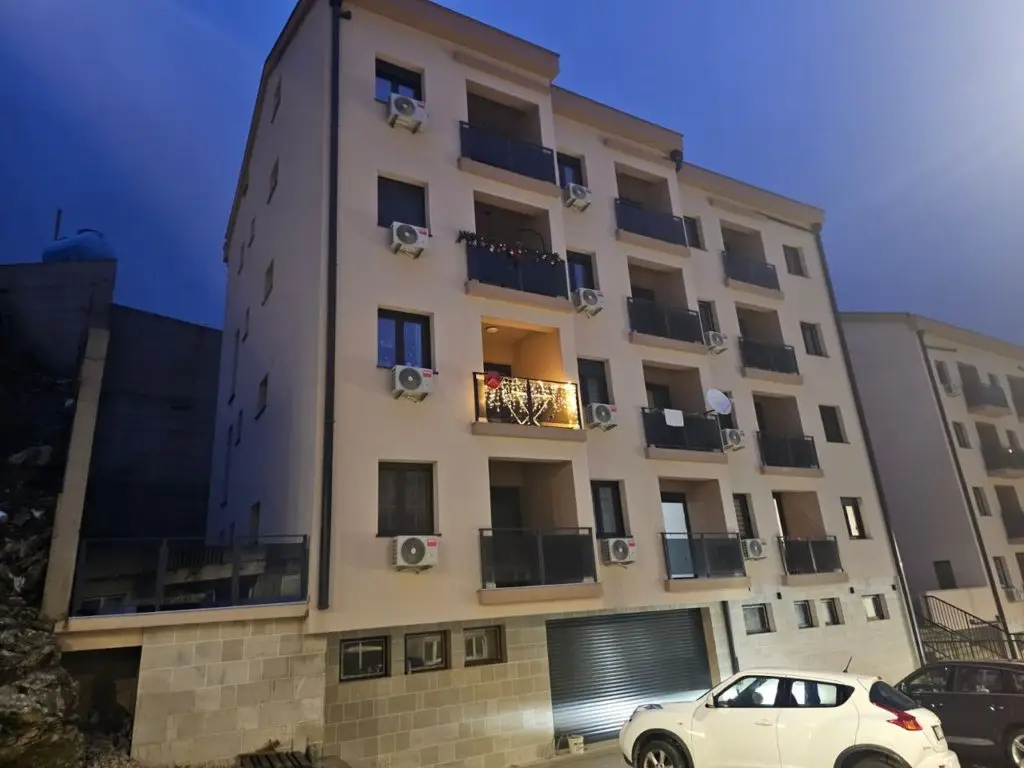 Apartment building with balconies and parked cars at dusk