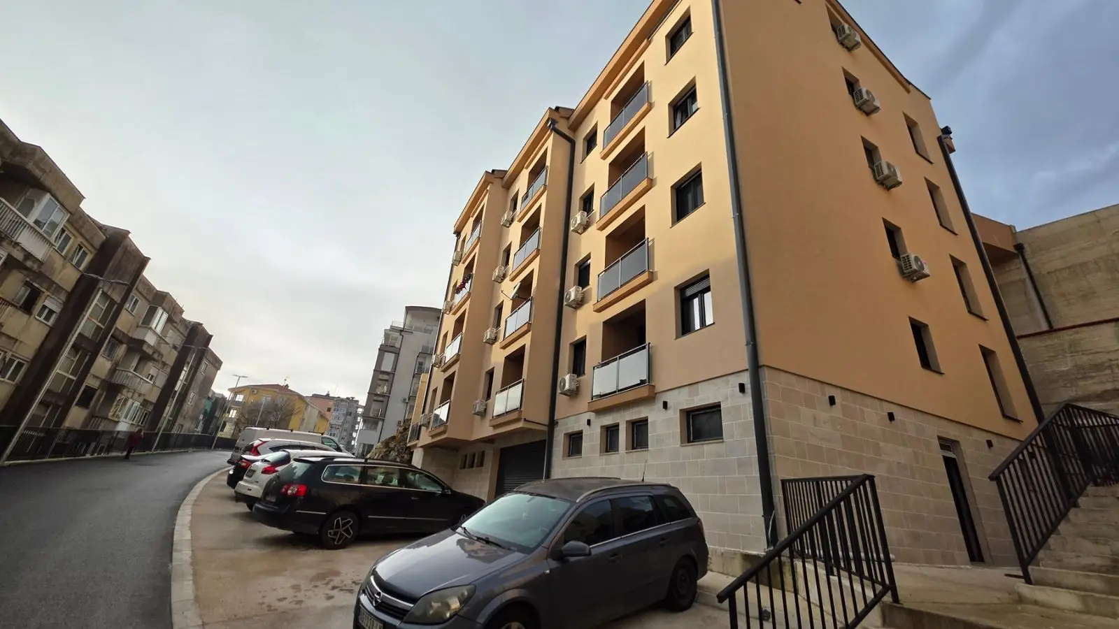 Apartment building with parked cars on a curved street