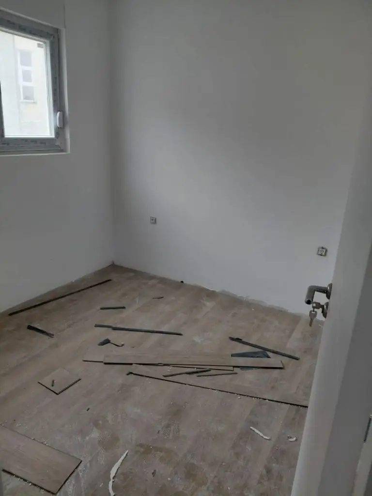 Empty unfinished room with window and scattered floor materials
