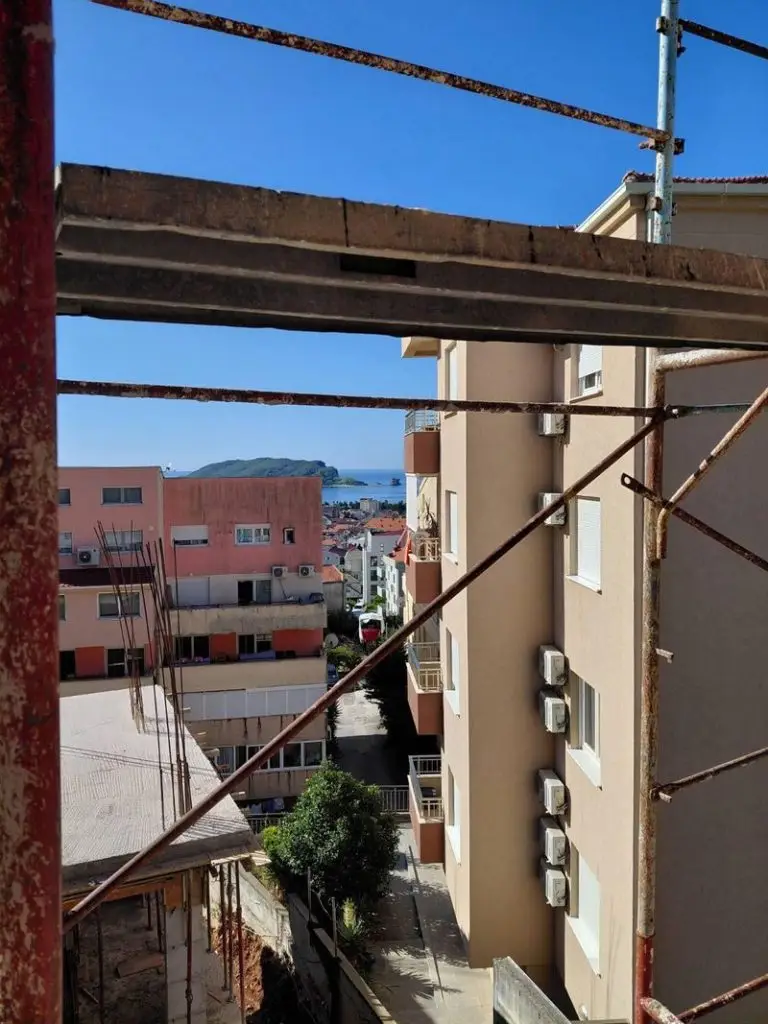 Rusty scaffolding framing apartment buildings and sea view