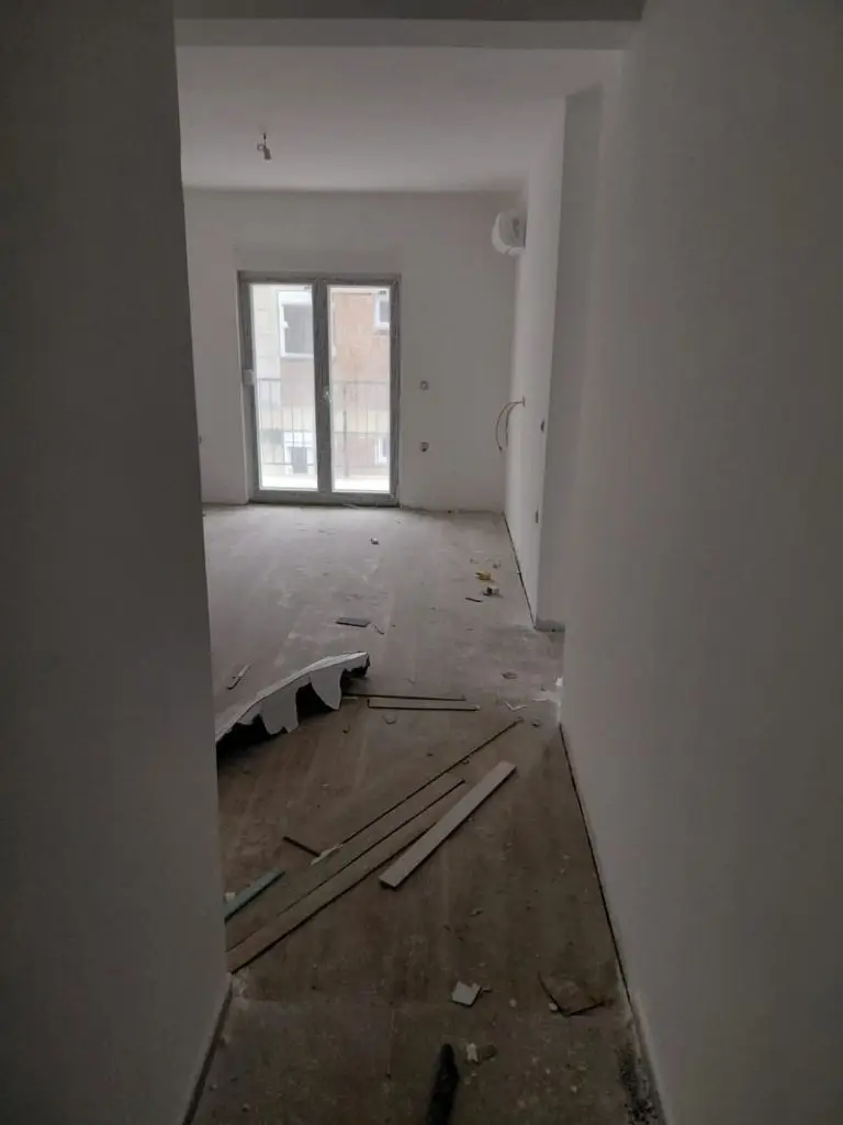 Unfinished room with debris and balcony doors
