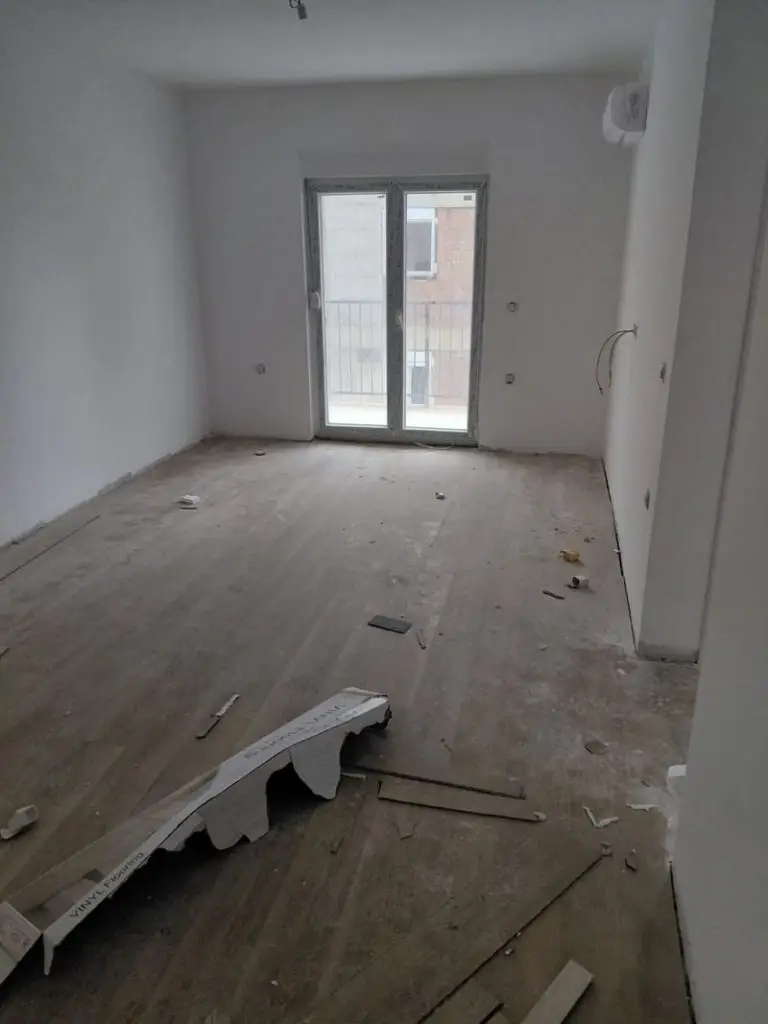 Unfinished room with balcony doors and debris on floor