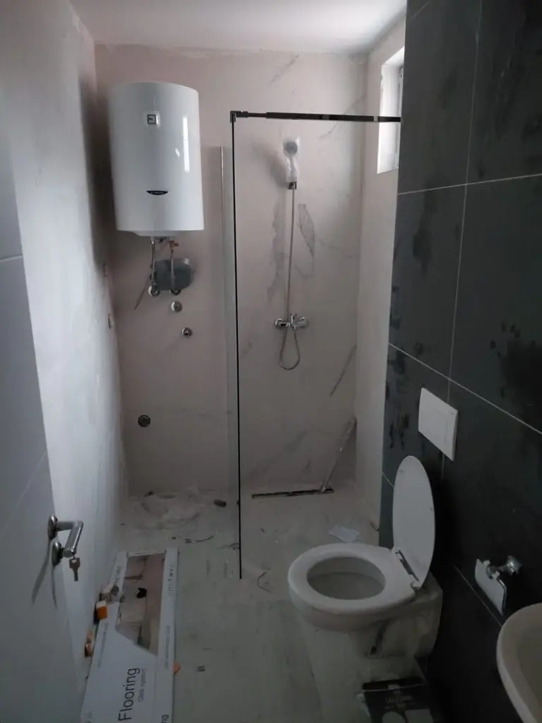 Unfinished bathroom with shower, toilet, and water heater