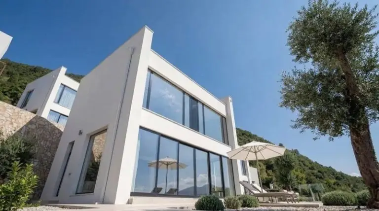 Modern white villa with large glass windows and terrace umbrellas